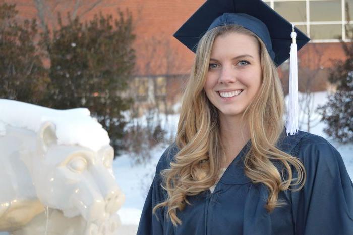 Sarah Lenhart in her cap and gown at graduation, beside the Lion